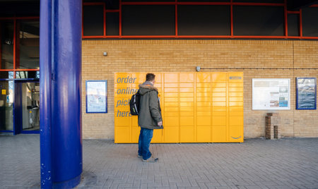 OXFORD, UNITED KINGDOM - MAR 2, 2017: Man looking at the Amazon locker orange delivery package...
