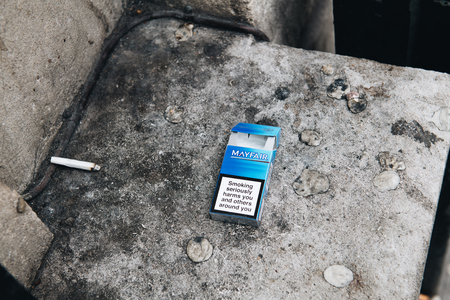 BRISTOL, UNITED KINGDOM - MAR 8, 2017: Mayfair cigarette pack thrown on the asphalt with large warning test: Smoking may reduce the blow flow and cause impotenceのeditorial素材