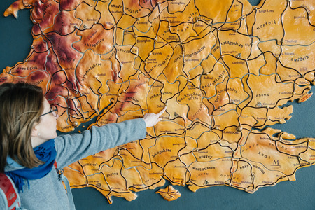 Woman poiinting to large United Kingdom map hanged on a wall to the city of Oxfordの写真素材