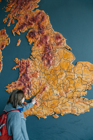 Woman poiinting to large United Kingdom map hanged on a wall to the city of Bristolの写真素材
