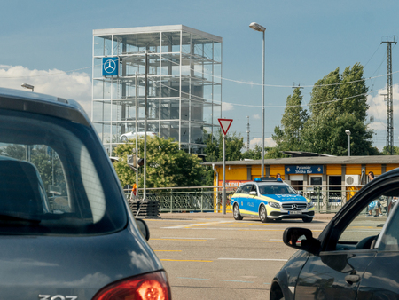 KEHL, GERMANY - JUL 14, 2017: German Police in Mercedes wagon car surveying the traffic on busy German street with glass cube with multiple Mercedes-Benz luxury cars insideのeditorial素材