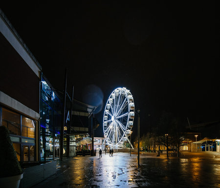 Sky View Observation Wheel in Anchor Square in central Bristol at night with people silhouette walking nearby on a rainy dayのeditorial素材