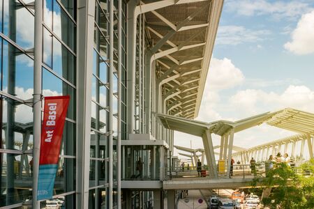 Basel, Switzerland - Circa 2017: Art Basel flag waving on the building of the EuroAirport Basel Mulhouse Freiburg with travelers commuters people walking in the airport areaのeditorial素材