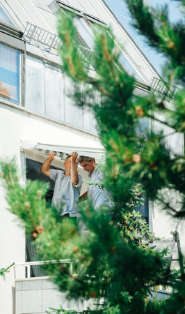 Paris, France - Jul 2, 2017: Male team installing sun protection awning  for sunshade on apartment...