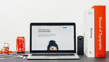PARIS, FRANCE - SEP 3, 2017: Minimalist creative room table with Safari Browser open on MacPook Pro laptop showcasing Apple Computers website with latest iPhone X 10 with face is used a password to unlock phoneのeditorial素材