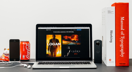 PARIS, FRANCE - SEP 13, 2017: Minimalist creative room table with Safari Browser open on MacPook Pro laptop showcasing Apple Computers website with latest Apple TV 4k with selction of 4k hdr moviesのeditorial素材