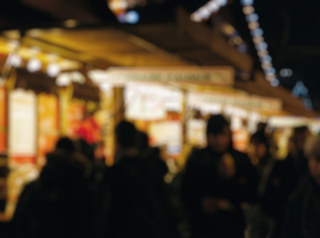 Illuminated Christmas fair kiosk market stall with loads of lovely handcrafted signs for home made crepes and sweet food people walkingの写真素材