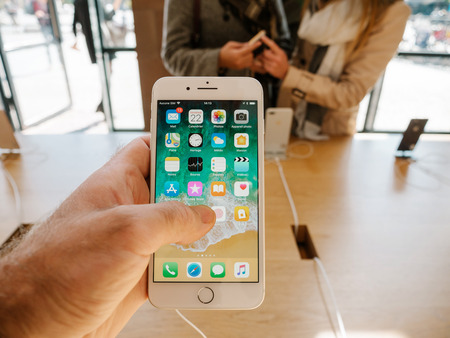 PARIS, FRANCE - SEP 22, 2017: New iPhone 8 and iPhone 8 Plus, as well the updated Apple Watch, Apple TV goes on sale today in Apple Store with man hand holding phone looking at the phone appsのeditorial素材