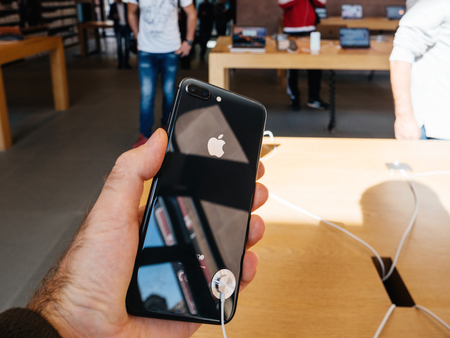 PARIS, FRANCE - SEP 22, 2017: New iPhone 8 and iPhone 8 Plus, as well the updated Apple Watch, Apple TV goes on sale today in Apple Store with customer holding the phone looking at the glass bodyのeditorial素材