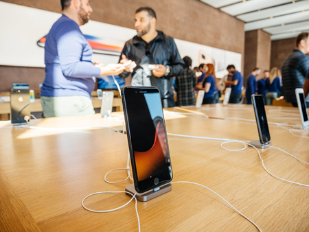 PARIS, FRANCE - SEP 22, 2017: New iPhone 8 and iPhone 8 Plus charging in docking station goes on sale today in Apple Store with middle East ethnicity customers holding admiring the phoneのeditorial素材
