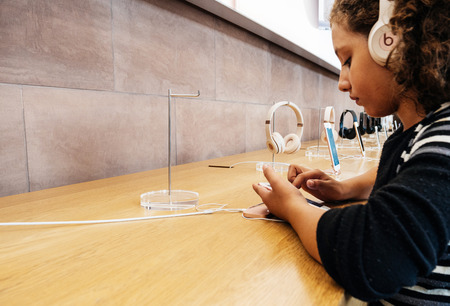 PARIS, FRANCE - SEP 22, 2017: New iPhone 8 and iPhone 8 Plus, as well the updated Apple Watch, Apple TV goes on sale today in Apple Store with young black ethnicity girls testing iphone with Beats by dr Dre headphonesのeditorial素材
