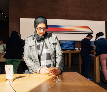 PARIS, FRANCE - SEP 22, 2017: New iPhone 8 and iPhone 8 Plus, as well the updated Apple Watch, Apple TV goes on sale today in Apple Store with middle-east ethnicity woman testing the new phoneのeditorial素材