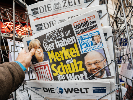 PARIS, FRANCE - SEP 23, 2017: Man buying latest newspaper Die Bild with with portrait of Angela Merkel And Martin Schulz before the election in Germany for the Chancellor of Germany, the head of the federal government, currently Angela Merkelのeditorial素材