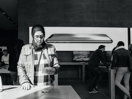PARIS, FRANCE - SEP 22, 2017: New iPhone 8 and iPhone 8 Plus, as well the updated Apple Watch, Apple TV goes on sale today in Apple Store with middle-east ethnicity woman testing the new phoneのeditorial素材