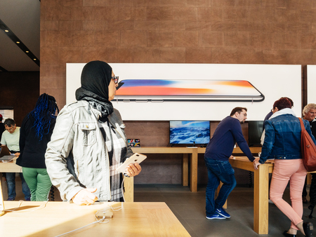 PARIS, FRANCE - SEP 22, 2017: New iPhone 8 and iPhone 8 Plus, as well the updated Apple Watch, Apple TV goes on sale today in Apple Store with middle-east ethnicity woman testing the new phoneのeditorial素材