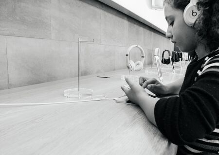 PARIS, FRANCE - SEP 22, 2017: New iPhone 8 and iPhone 8 Plus, as well the updated Apple Watch, Apple TV goes on sale today in Apple Store with young black ethnicity girls testing iphone with Beats headphonesのeditorial素材