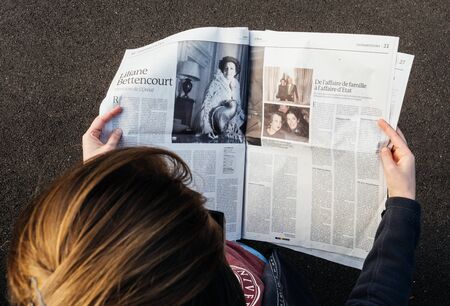 PARIS; FRANCE - SEP 24; 2017: View from above of woman reading latest newspaper Le Monde with portrait of Liliane Bettencourt. Liliane Henriette Charlotte Bettencourt was a French heiress, socialite and businesswoman. She was one of the principal shareholのeditorial素材