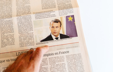 PARIS, FRANCE - SEP 25, 2017: Man reading international newspaper about politics of French President Emmanuel Macronのeditorial素材