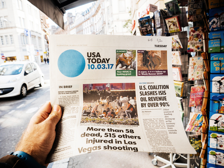 PARIS, FRANCE - OCT 3, 2017: Man buying USA Today newspaper with socking title and photo at press kiosk about the 2017 Las Vegas Strip shooting in United States with about 60 fatalities and 527 injuriesのeditorial素材