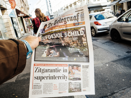 PARIS, FRANCE - OCT 3, 2017: Man buying De Telegraaf newspaper with socking title and photo at press kiosk about the 2017 Las Vegas Strip shooting in United States with about 60 fatalities and 527 injuriesのeditorial素材