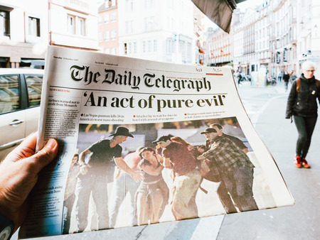 PARIS, FRANCE - OCT 3, 2017: Man buying The Daily Telegraph newspaper with socking title Pure Evil and photo at press kiosk about the 2017 Las Vegas Strip shooting in United States with about 60 fatalities and 527 injuriesのeditorial素材