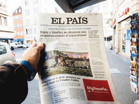 PARIS, FRANCE - OCT 3, 2017: Man buying Spanish El Pais  newspaper with socking title and photo at press kiosk about the 2017 Las Vegas Strip shooting in United States with about 60 fatalities and 527 injuriesのeditorial素材