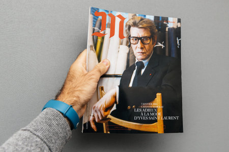 PARIS, FRANCE - OCT 4, 2017: Man holding M Magazine le monde with Yves Saint laurent fashion icon on...