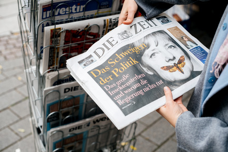 STRASBOURG, FRANCE - OCT 28, 2017: Woman reading buying German Die Zeit newspaper at press kiosk featuring Angela Merkel and tilte The Silenece of Politicsのeditorial素材