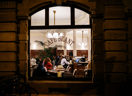 STRASBOURG, FRANCE - NOV 21, 2017: Tourists and locals drinking a warm coffee or tea inside the Brant Cafe in Strasbourg - view from the street at nightのeditorial素材