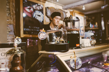STRASBOURG, FRANCE - NOV 21, 2017: Barista behind the counter preparing a chocolate drink in an ice-cream shopのeditorial素材