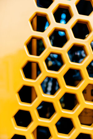 Metallic grill tractor part painted in yellow with multiple hexagonal shapes for ventilation and hot...
