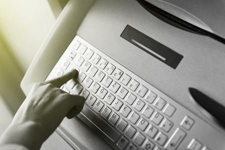 Modern filter over woman finger pressing the A letter button on the metallic keyboard of ATM Automatic Teller Machine to retrieve withdrawal money or use other finance instrumentの写真素材