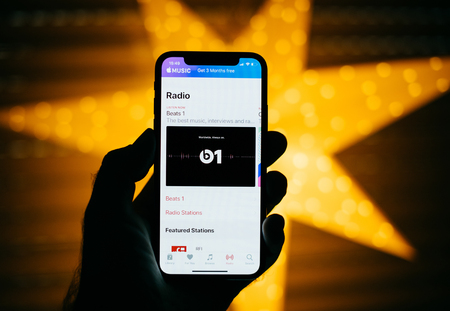 PARIS, FRANCE - NOV 10, 2017: Man holding the new Apple iPhone X 10 Display with yellow star bokeh background featuring Radio music in the iTunes with Beats 1のeditorial素材