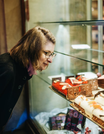 Woman buying sweets a the patisserie bakery store window in French city during Christmas winter holidays の写真素材