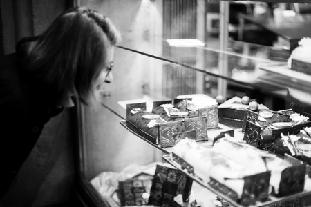 Woman buying sweets a the patisserie bakery store window in French city during Christmas winter holidays の写真素材