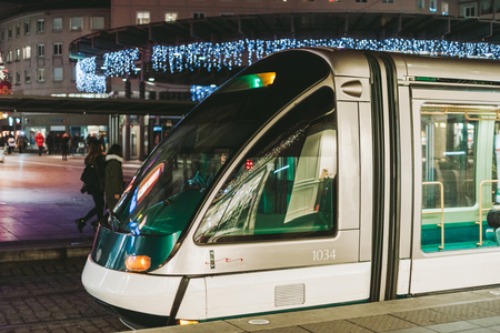 STRASBOURG, FRANCE - DEC 23, 2016; Tramway at night in French city of Strasbourg with pedestrians and defocused lights of Christmas decorations in the backgroundのeditorial素材