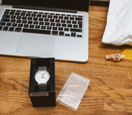 PARIS, FRANCE - DEC 5, 2017: Man unboxing new Braun German watch clock on work table with Apple MacBook retina laptop workingのeditorial素材