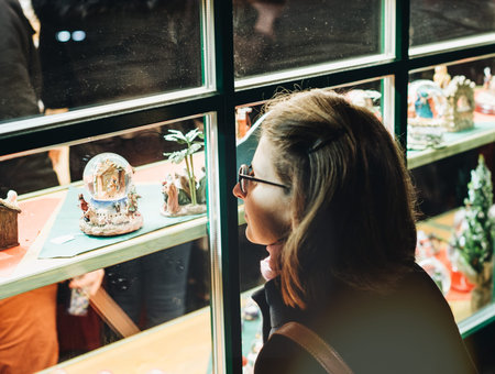 Woman admiring the Christmas gifts souvenirs in through the windows of chalet of Christmas Market atmosphere in Strasbourg, Alsaceの写真素材