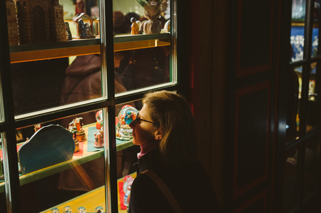 Woman admiring the Christmas gifts souvenirs in through the windows of chalet of Christmas Market atmosphere in Strasbourg, Alsaceの写真素材