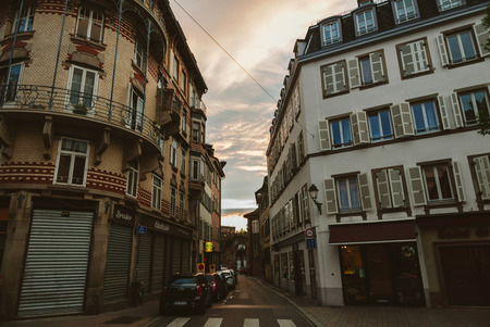 STRASBOURG, FRANCE - MAY 29, 2017: Luxury French architecure and cars driving on the tiny cozy street at dusk with beautiful sunset aboveのeditorial素材