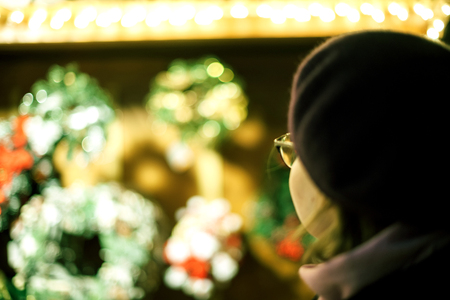 Rear view of beautiful French woman wearing trendy fashion beret hat with defocused bokeh lights of Christmas Market in the backgroundの写真素材