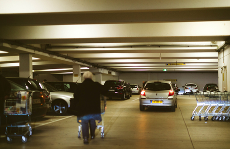 FRANKFURT, GERMANY - DEC 21, 2016: Outdoor supermarket witn senior man pushing shopping grocery cart, cars parkingのeditorial素材