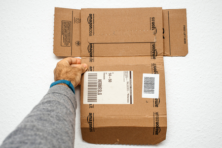 PARIS, FRANCE - DEC 18, 2017: Man holding new Amazon Prime cardboard box against white backgroundのeditorial素材