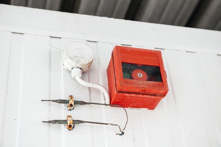 Alarm setting on the wall with two steel pipes and red cage with key button の写真素材