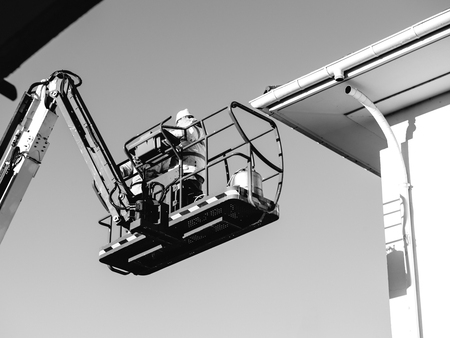 People working on the elevated platform near the roof of a houseの写真素材