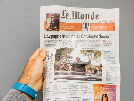 LYON, FRANCE - APR 10, 2017: Man holding le monde french newspaper POV with international news from Spain to France and USAのeditorial素材