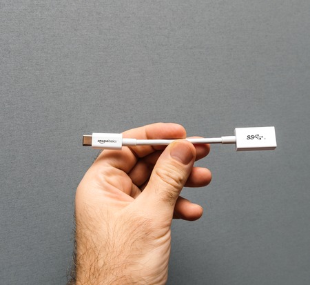 PARIS, FRANCE - JAN 23, 2018: Man holding against gray background a new white cable from Amazon Basics AmazonBasics with USB-C to USB  Adapterのeditorial素材