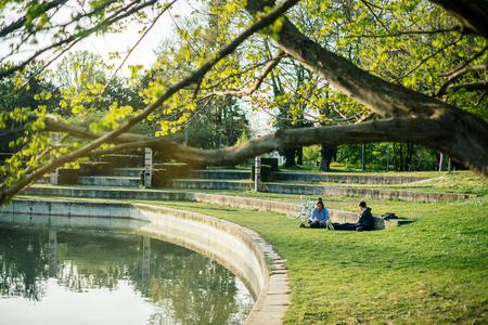 STRASBOURG, FRANCE - APR 7, 2017: French male friends resting on grass enjoying the sun on an early spring day in Strasbourg Orangerie public parkのeditorial素材