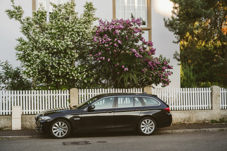 PARIS, FRANCE - APR 21, 2017: New black BMW 5 Series wagon on the street of Paris with lilac flower and beautiful fence in the backgroundのeditorial素材
