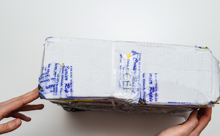 PARIS, FRANCE - JAN 9 2017: Woman holdinng broken parcel covered with safety scotch adhesive band from Posta Moldovei, Moldovan postal service - white table backgroundのeditorial素材